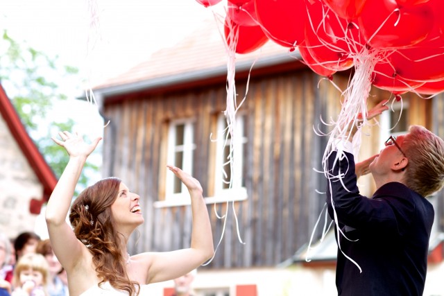 Bruidspaar laat rode ballonnen vliegen.