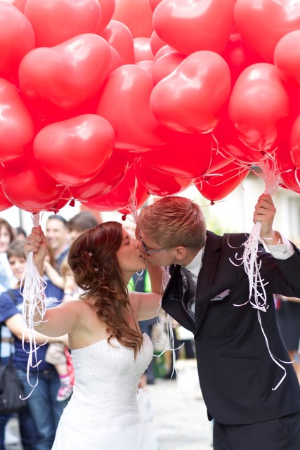 Bruidspaar onder rode ballonnen